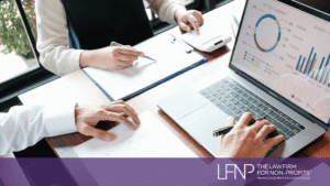 Two nonprofit professionals review financial reports and budget charts on a laptop while discussing public charity compliance and IRS reporting requirements. LFNP branding displayed at bottom of image.
